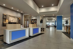 A hotel reception area with a modern design, featuring a reception desk, a seating area, and a view of the dining space. - Holiday Inn Express Hotel & Suites Austell - Powder Springs by IHG (Austell)