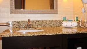 A bathroom with a granite countertop, a sink, a mirror, and toiletries. - Holiday Inn Express Hotel & Suites Austell - Powder Springs by IHG (Austell)