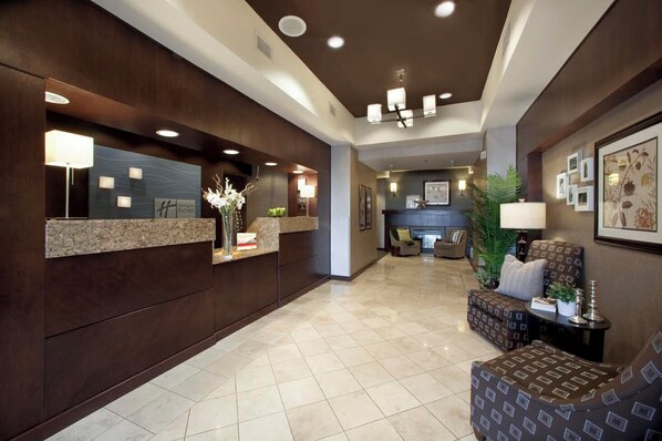 A hotel lobby with a reception desk, seating area, and a fireplace.