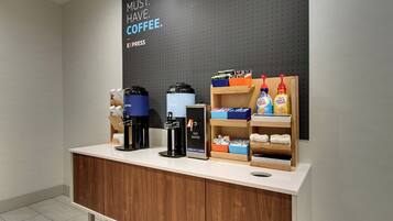 A coffee station with a coffee machine, a hot water dispenser, and coffee pods on a counter.