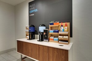A coffee station with a coffee machine, a hot water dispenser, and coffee pods on a counter. - Holiday Inn Express Hotel & Suites Austell - Powder Springs by IHG (Austell)