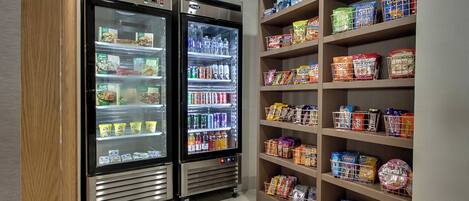 Ein Selbstbedienungsbereich für Snacks und Getränke mit Kühlregalen und Regalen, gefüllt mit verschiedenen Produkten.