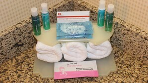 A bathroom counter with toiletries including bath gel, lotion, shampoo, and a makeup remover wipe. - Holiday Inn Express Hotel & Suites Austell - Powder Springs by IHG (Austell)