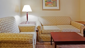 A living room with patterned sofas, a small table, and a lamp. - Holiday Inn Express Hotel & Suites Austell - Powder Springs by IHG (Austell)