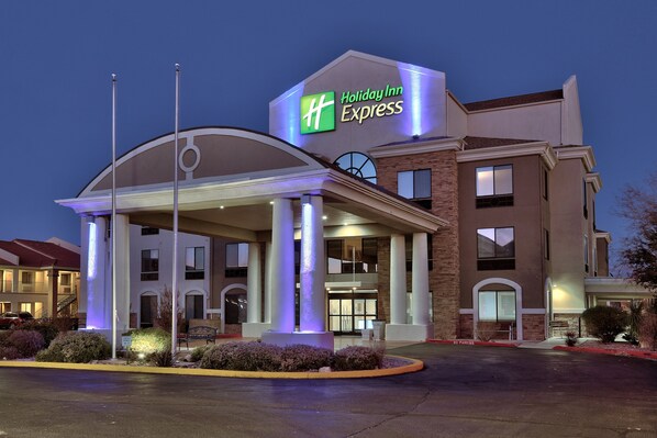 Edificio de Holiday Inn Express con un cartel llamativo, un acceso cubierto y una zona ajardinada con arbustos.