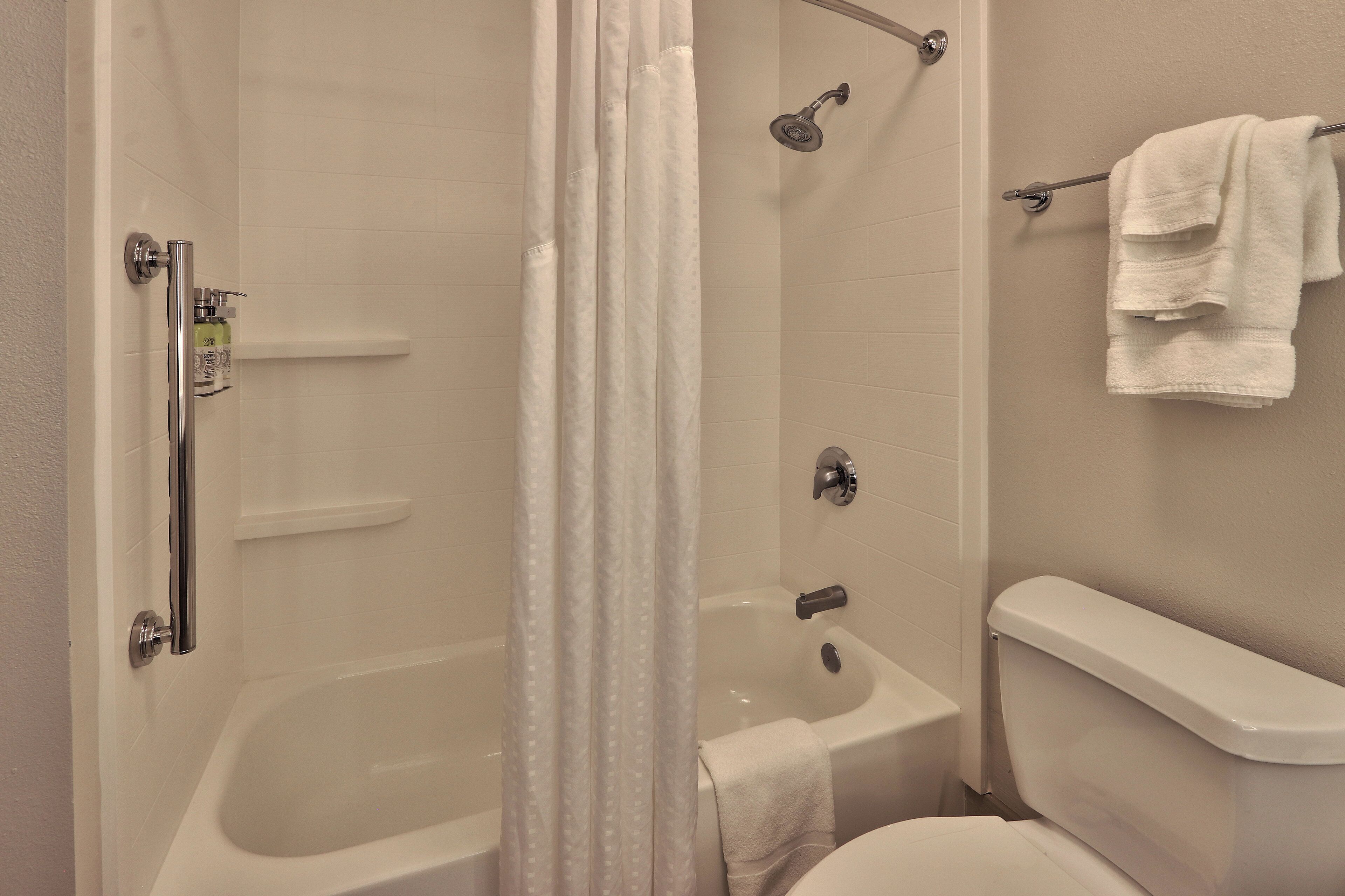 A bathroom with a bathtub, shower, toilet, and a towel rack.