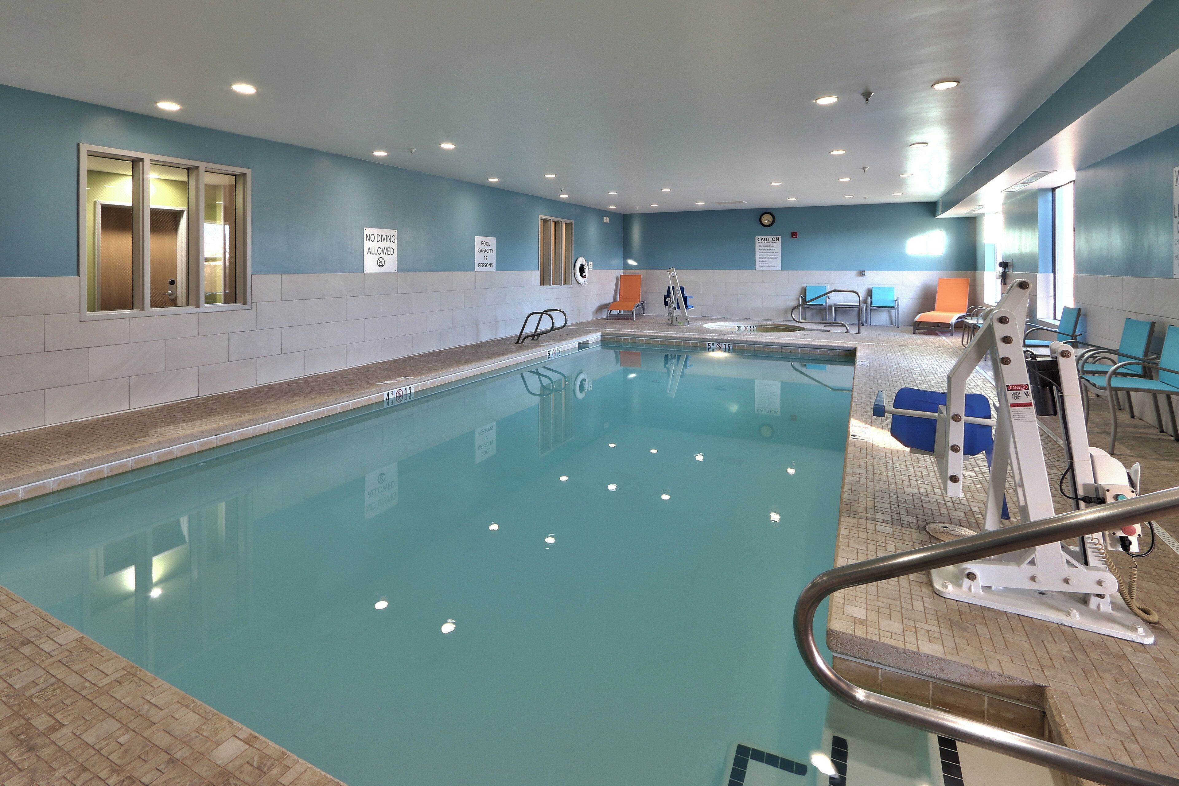 Una piscina interior con un cartel de no buceo, un indicador de capacidad de la piscina y un letrero de precaución.