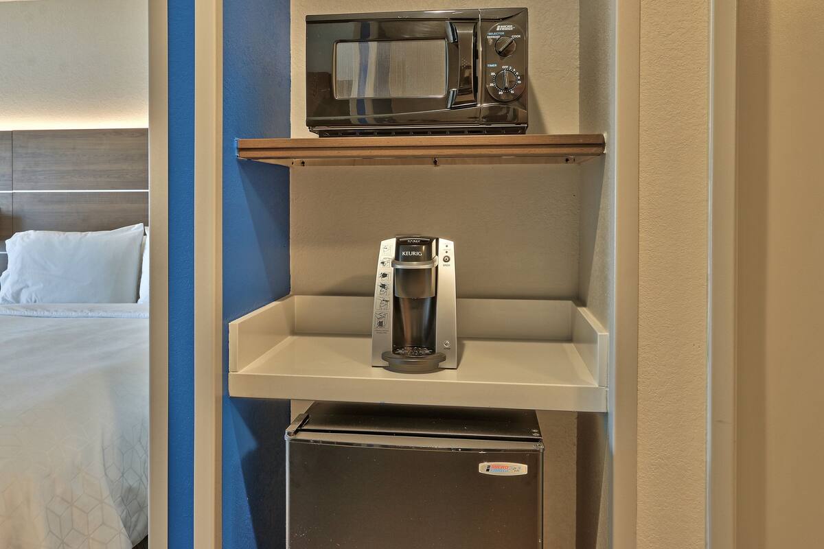 Eine Küchenzeile mit Mikrowelle, Kaffeemaschine und Kühlschrank.