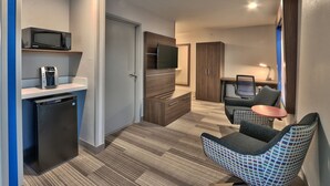 A compact hotel room with a kitchenette, a flat-screen TV, a small dining table, and a seating area with a patterned chair. - Holiday Inn Express Socorro by IHG (Socorro)