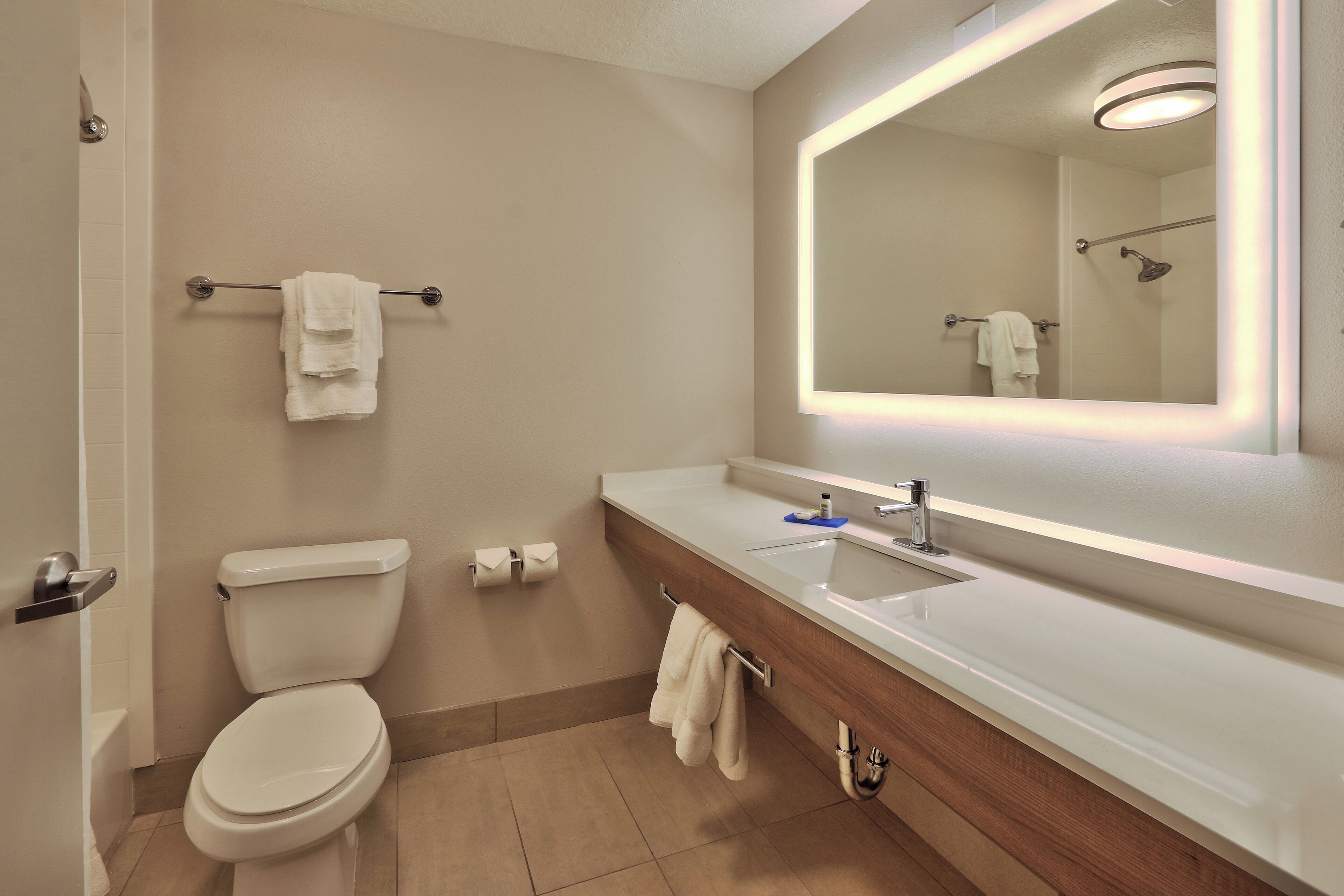 A modern bathroom with a toilet, sink, and mirror.