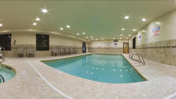 An indoor swimming pool with tiled walls and a tiled floor, surrounded by lounge chairs and a changing room. - Holiday Inn Express Socorro by IHG (Socorro)