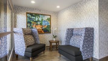 A room with two sofas, a small table, and a painting on the wall.