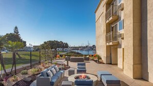 A patio with outdoor furniture, a fire pit, and a view of a marina. - Hampton Inn Channel Islands Harbor/Oxnard (Oxnard)