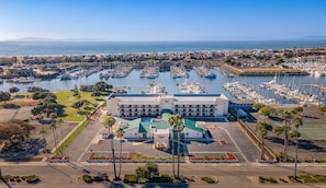 A marina with numerous boats docked, a large building with a green roof, and a clear view of the ocean. - Hampton Inn Channel Islands Harbor/Oxnard (Oxnard)