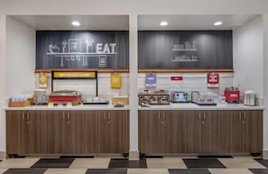 A modern kitchen with wooden cabinets, a chalkboard wall, and various breakfast items.