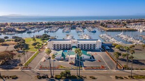 A marina with numerous boats docked, a large building with a green roof, and a clear view of the ocean. - Hampton Inn Channel Islands Harbor/Oxnard (Oxnard)