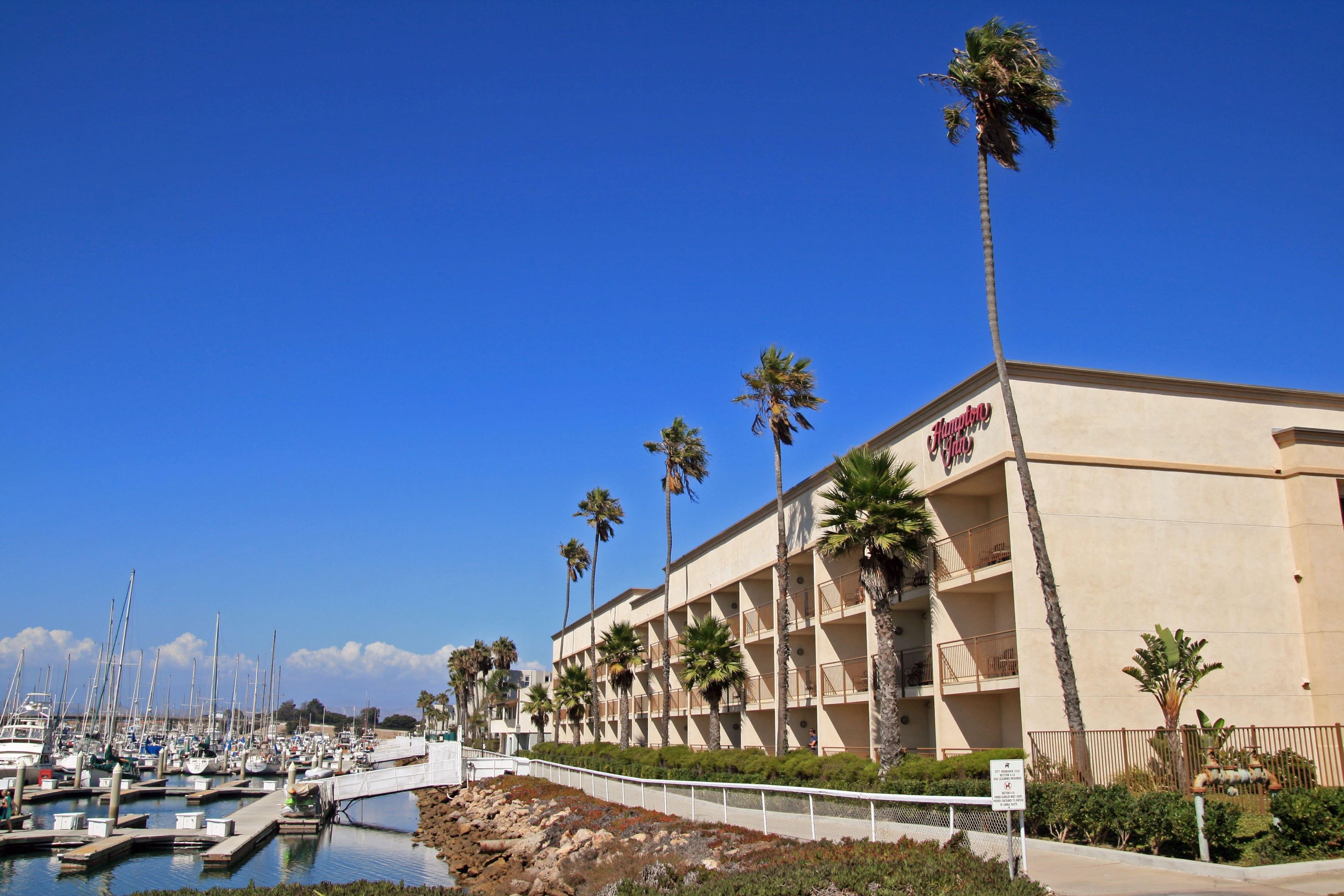 A hotel with a marina, multiple balconies, and palm trees.