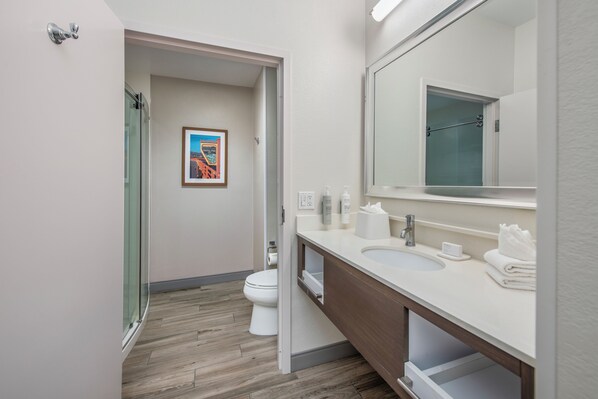 A modern bathroom with a glass shower enclosure, a white sink with a vanity, and a framed picture on the wall. - Hampton Inn Channel Islands Harbor/Oxnard (Oxnard)