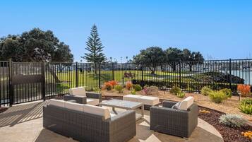 An outdoor patio with wicker furniture and a view of a landscaped area with trees and shrubs.