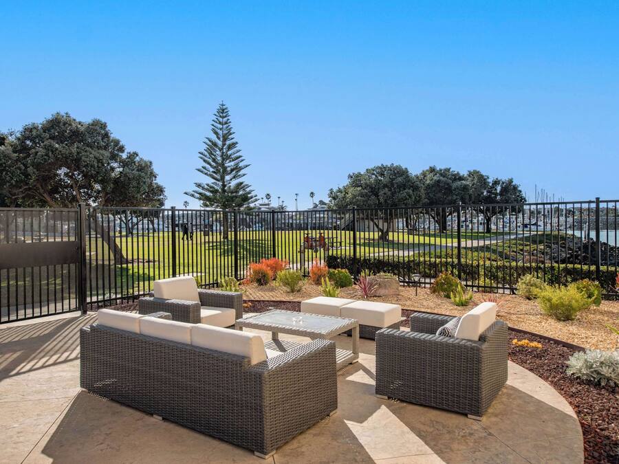 An outdoor patio with wicker furniture and a view of a landscaped area with trees and shrubs.