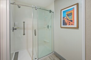 A glass-enclosed shower with a handrail, a framed picture on the wall, and a white tiled floor. - Hampton Inn Channel Islands Harbor/Oxnard (Oxnard)