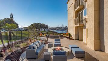 An outdoor patio with seating and a fire pit, overlooking a marina.
