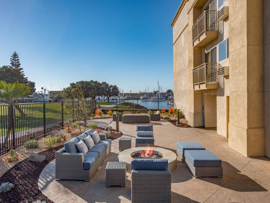 An outdoor patio with seating and a fire pit, overlooking a marina.