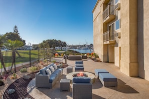 An outdoor patio with seating and a fire pit, overlooking a marina. - Hampton Inn Channel Islands Harbor/Oxnard (Oxnard)