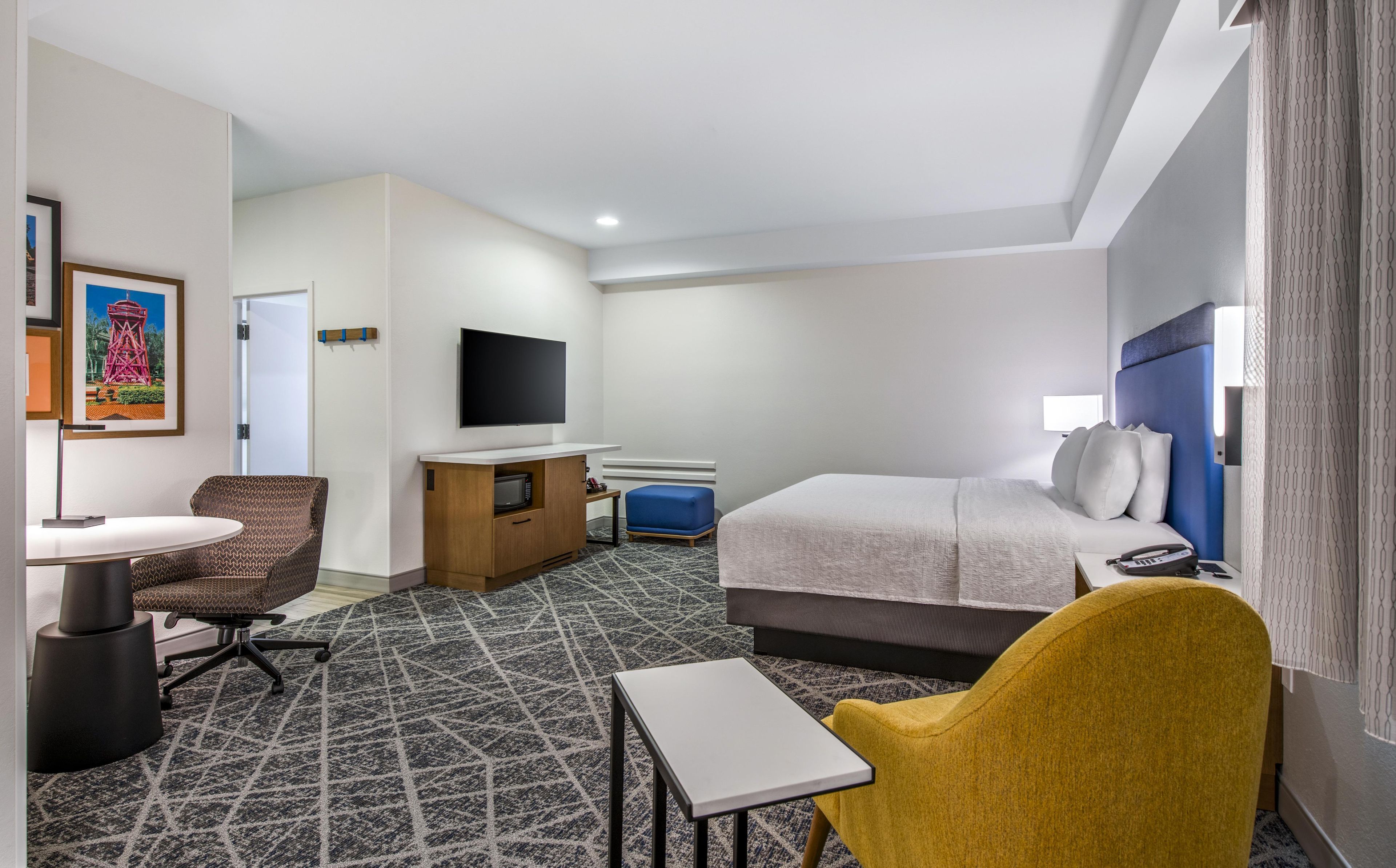 Een hotelkamer met een bed, een bureau, een stoel, een televisie en een klein tafeltje.