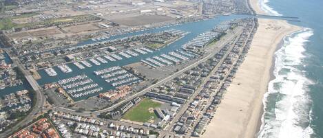 An aerial view of a coastal city with a marina, residential areas, and a beach.