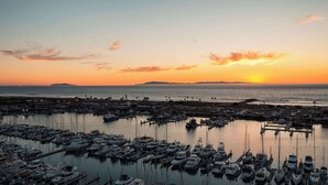A marina with numerous boats docked, a sunset in the background, and a view of the coastline. - Hampton Inn Channel Islands Harbor/Oxnard (Oxnard)