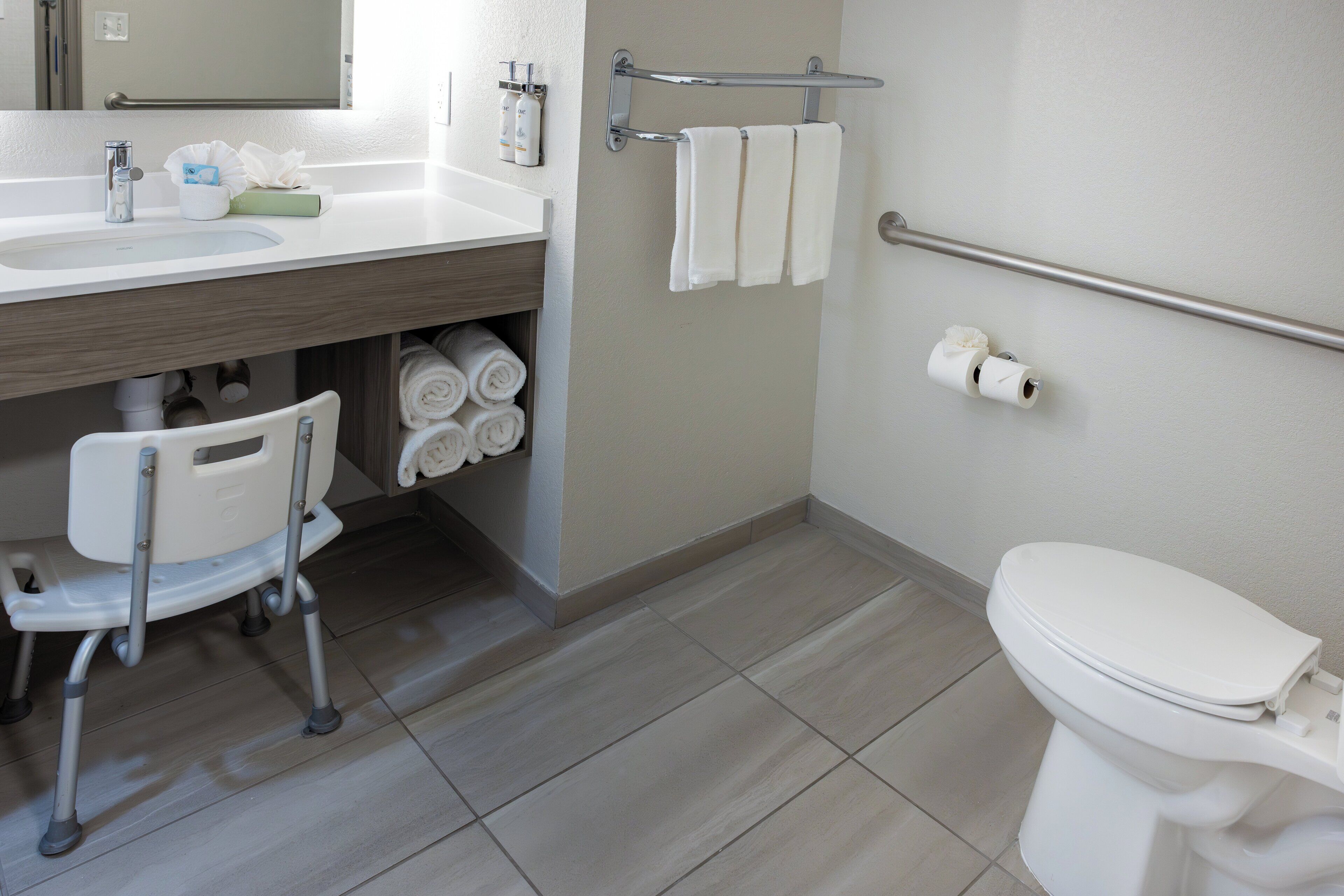 Een moderne badkamer met toilet, wastafel en een rolstoelstoel.
