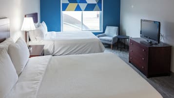A hotel room with two beds, a TV, a chair, and a desk.