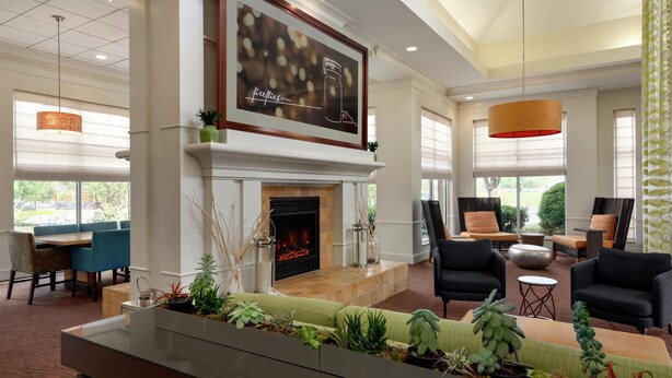 A spacious lobby with a fireplace, comfortable seating, and large windows. - Hilton Garden Inn Harrisburg East (Harrisburg)