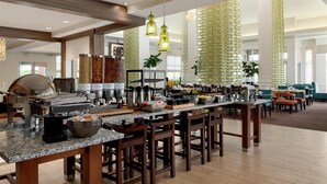 A spacious kitchen with a long counter, bar stools, and various cooking appliances. - Hilton Garden Inn Harrisburg East (Harrisburg)