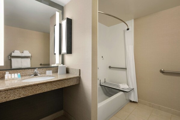 A bathroom with a sink, mirror, and shower area.