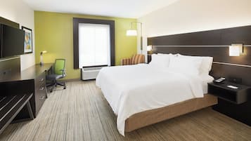 Una habitación de hotel con cama, escritorio, silla, televisor y ventana.