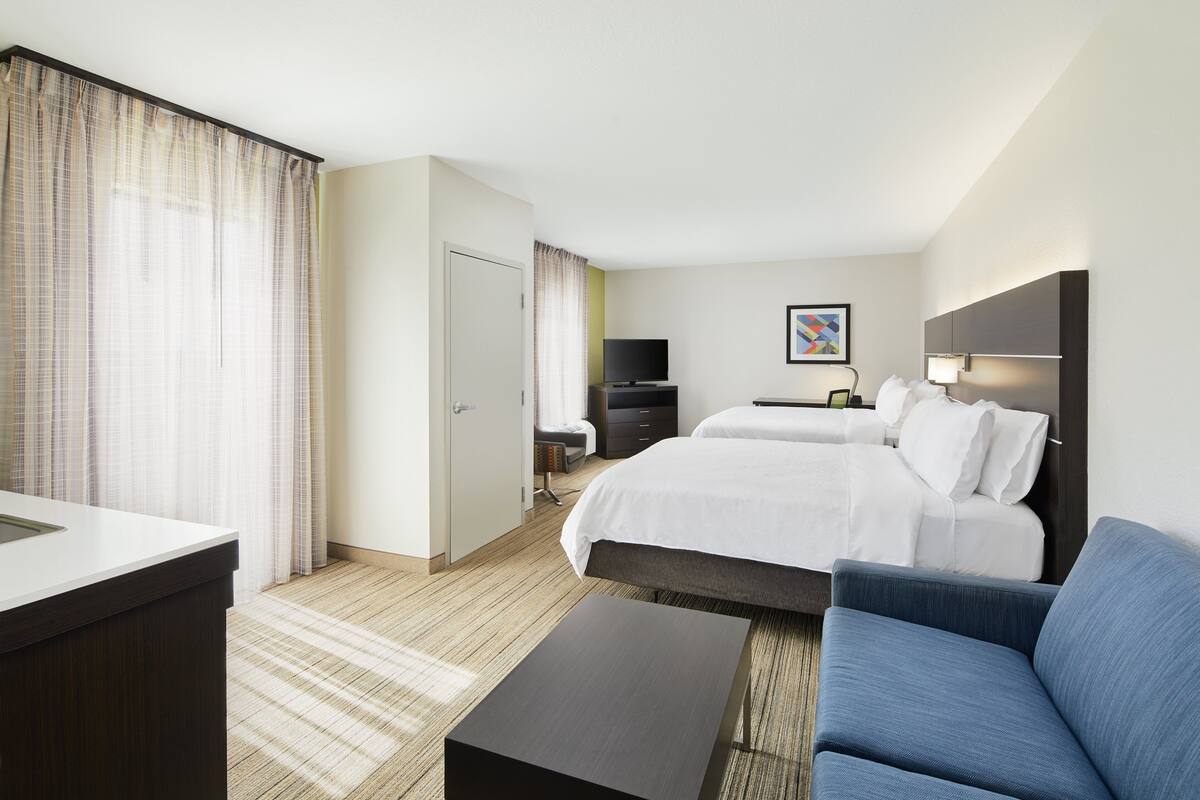A hotel room with a bed, a desk, a TV, and a couch.