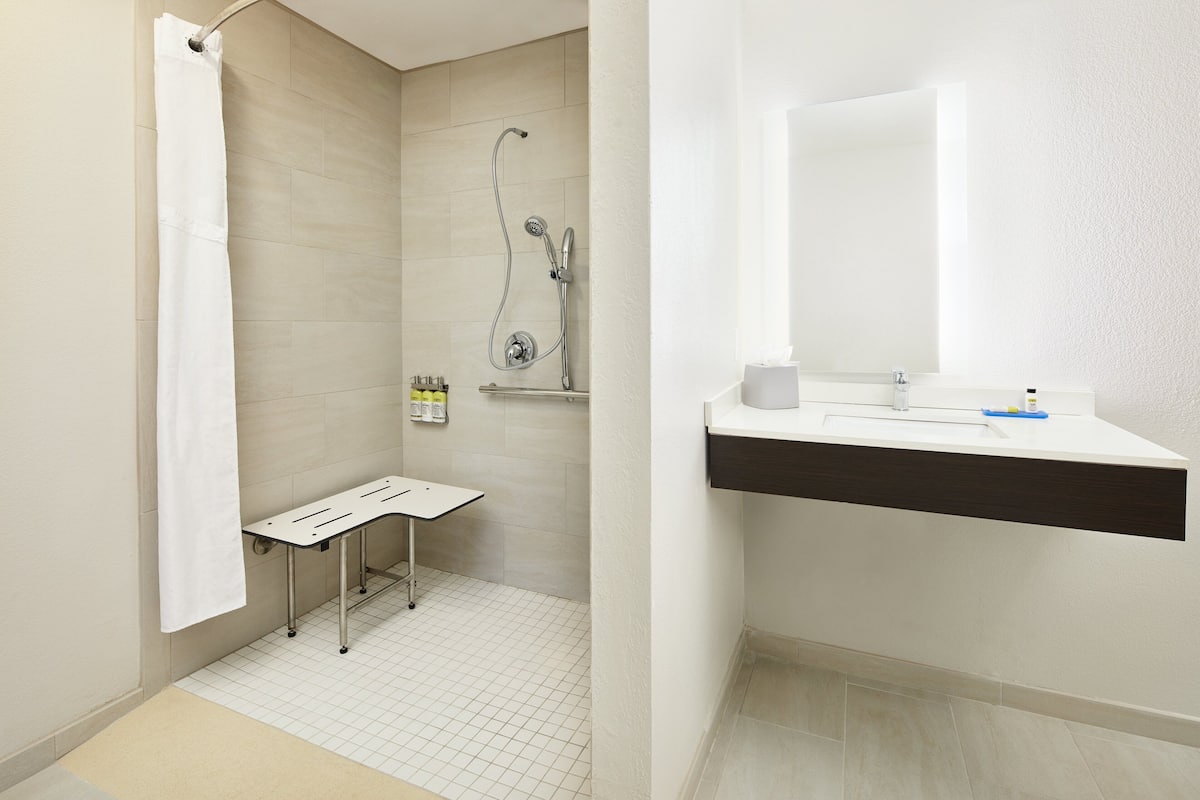 A bathroom with a shower, a sink, and a mirror.