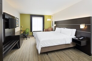 Una habitación de hotel con cama, escritorio, silla, televisor y ventana.
