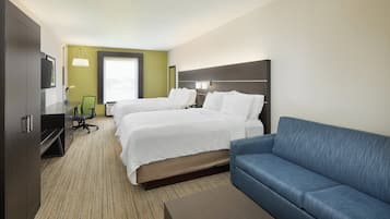 A hotel room with two beds, a sofa, a desk, and a television.