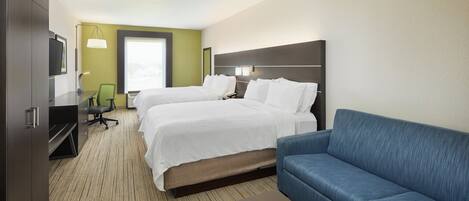 Ein Hotelzimmer mit zwei Betten, einem Sofa, einem Schreibtisch und einem Fernseher.