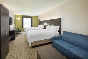Habitación de hotel con dos camas, un sofá, un escritorio y una televisión.