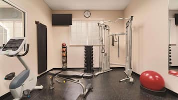 A gym with exercise equipment, a clock, and a window.
