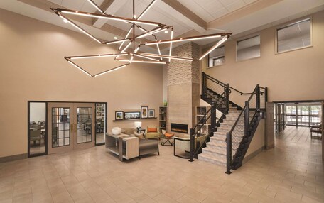 A spacious interior with a modern staircase, a fireplace, and a seating area with a coffee table and chairs.