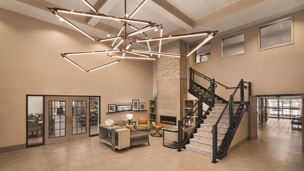A spacious interior with a modern staircase, a fireplace, and a seating area with a coffee table and chairs. - Country Inn & Suites by Radisson, Grand Rapids East, MI (Grand Rapids)