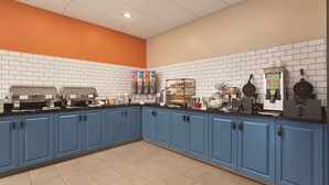 A kitchen area with blue cabinets, white tiled walls, and various cooking appliances.