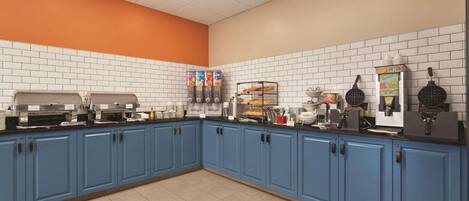 A kitchen area with blue cabinets, white tiled walls, and various cooking appliances.