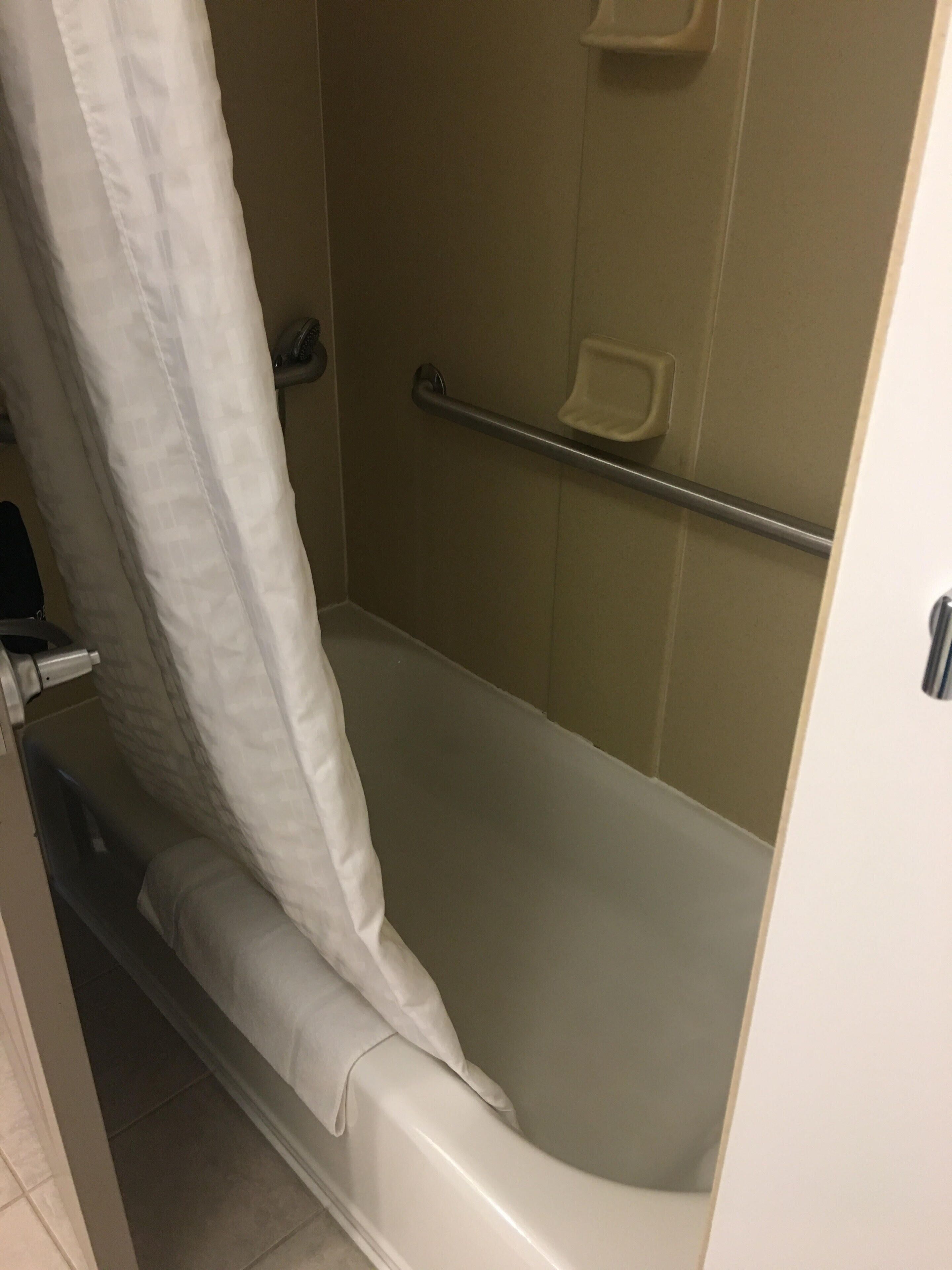 A bathroom with a bathtub, a shower curtain, and a towel rack.