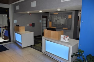 Un área de recepción con dos mostradores, una pantalla digital y un panel informativo en la pared.